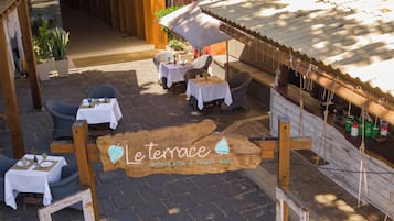 En uteservering med bord och stolar, en hängmatta och en träskylt med texten "Le Terrace".