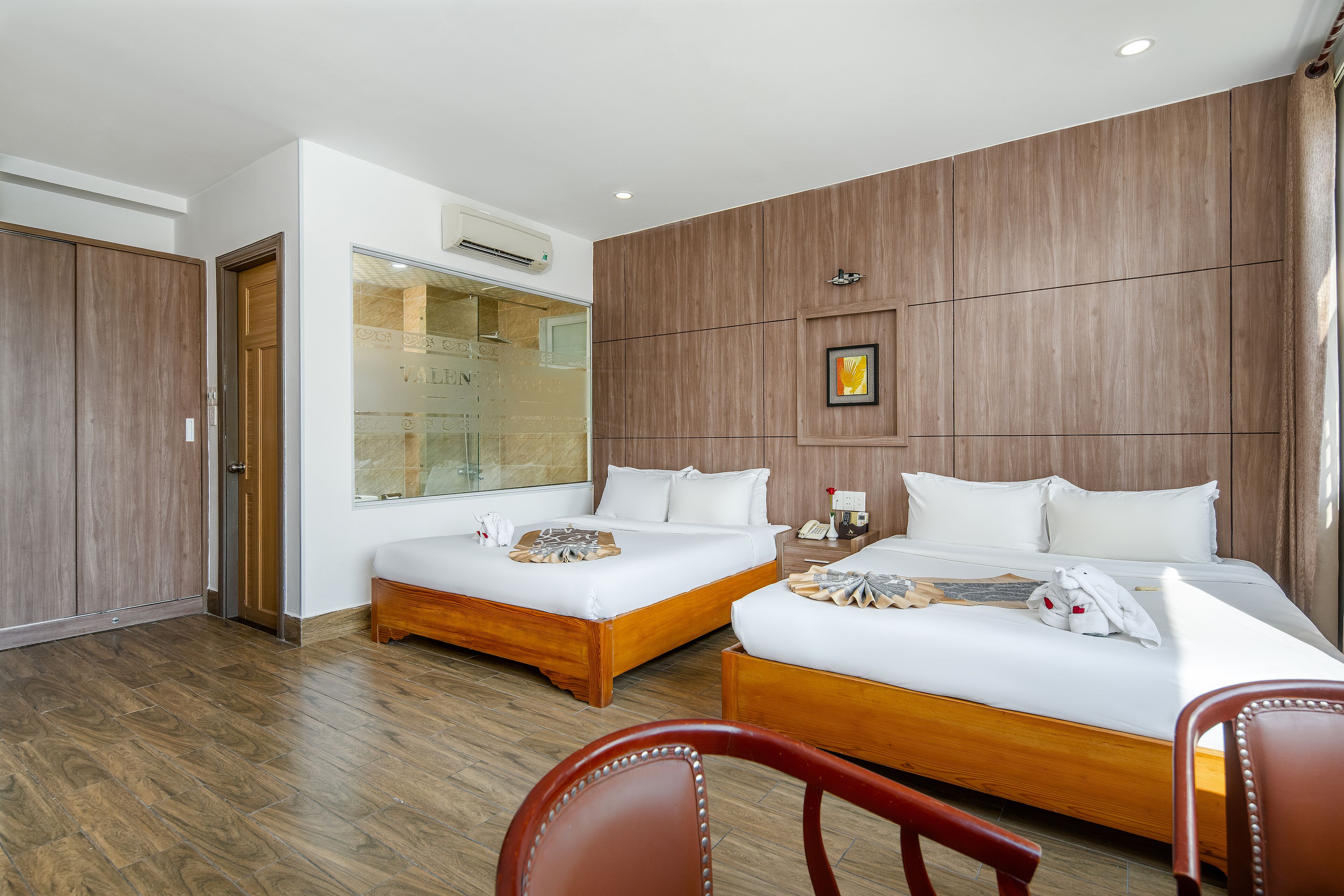 Een hotelkamer met twee bedden, houten vloeren, een grote spiegel en een houten hoofdeinde.