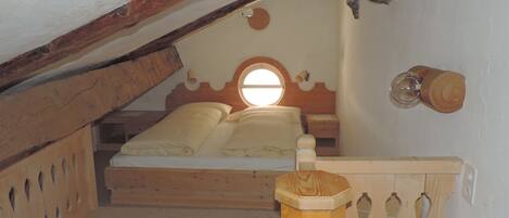 Un dormitorio con cama de madera, una ventana y cabecero de madera.