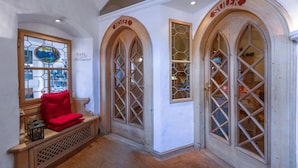 A hotel lobby with arched windows, a bench with a red cushion, and a stained glass window. - Hotel Klarer (Zuoz)