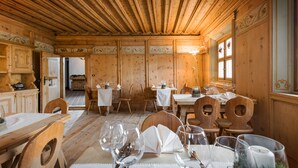 A wooden interior with tables set for dining, featuring chairs and wine glasses. - Hotel Klarer (Zuoz)