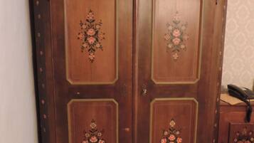 Een houten garderobe met bloemmotieven, een telefoon bovenop en een behang met patroon.