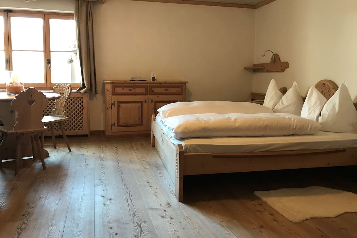 Un dormitorio con cama de madera, mesita de noche, cómoda y ventana con cortinas.