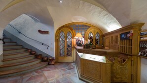 A grand staircase with copper pots, a bar area with a wine glass display, and a sign reading "Selita". - Hotel Klarer (Zuoz)