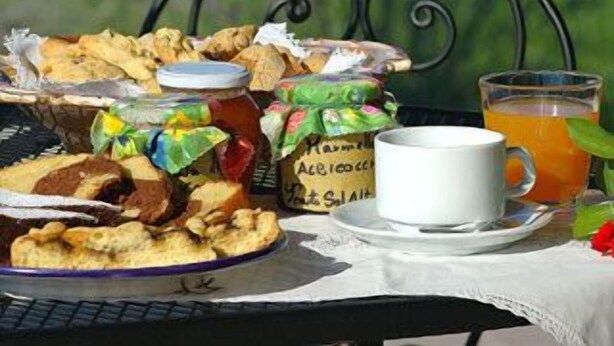 Une table dressée à l’extérieur, avec une variété de plats, une tasse de thé et une chaise en métal.