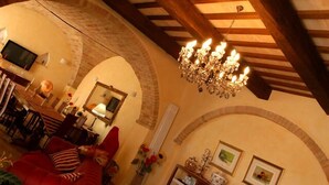 Un salon chaleureux avec un lustre, un coin repas et un téléviseur fixé au mur.
