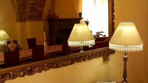 Une pièce dotée d’un grand miroir qui reflète une table avec deux lampes, une cheminée et un livre posé sur une table d’appoint.