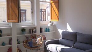 Una sala moderna con un sofá, una mesa de comedor para dos personas y una estantería.