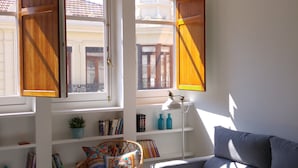 Un salón moderno con un sofá azul, una silla de mimbre y una mesita.
