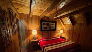 Una habitación acogedora de madera con una cama, dos lámparas de noche y una obra de arte enmarcada en la pared.