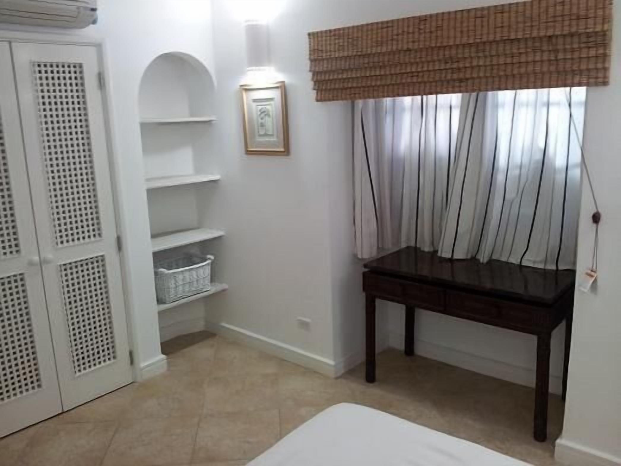 A room with a bed, a desk, a wardrobe, and a window with curtains.