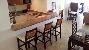 Une cuisine compacte dotée d’un îlot central, de tabourets de bar et d’un coin repas avec une table et des chaises.