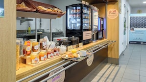 Una barra de desayuno con diferentes opciones de alimentos, un refrigerador y un letrero que dice "Le Café des gourmands".