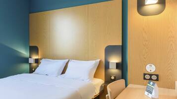Une chambre d’hôtel avec un lit, des tables de chevet et un bureau avec une chaise. On y trouve des appliques murales et un panneau fixé au mur.