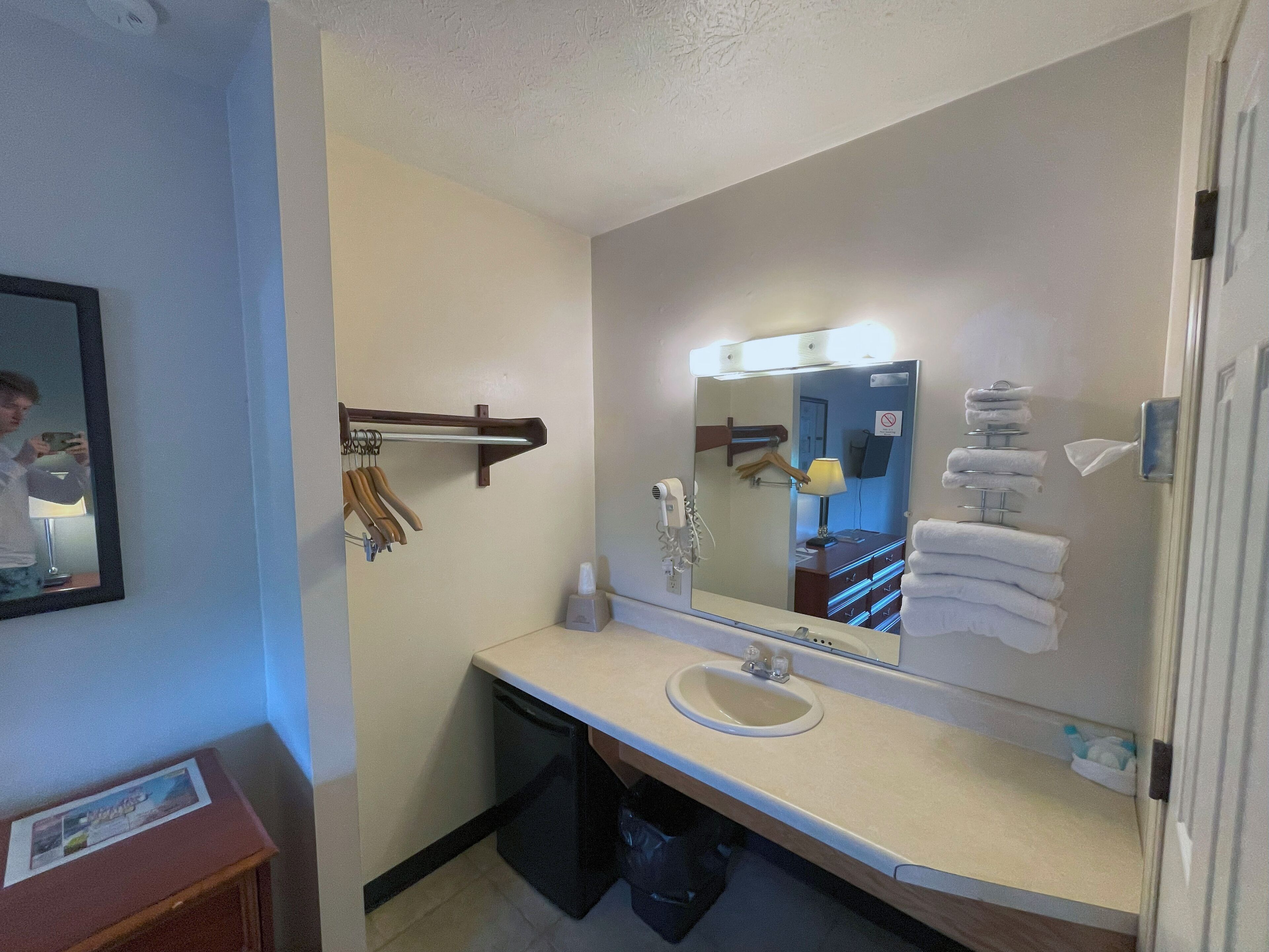 Un baño con lavamanos, espejo, toallero y secador de pelo.