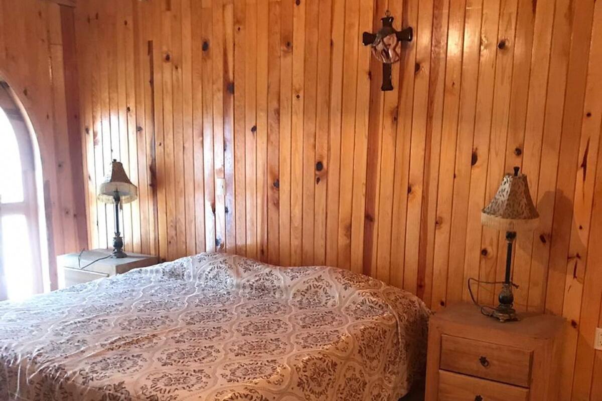 A bedroom with a bed, a nightstand, and a cross on the wall.