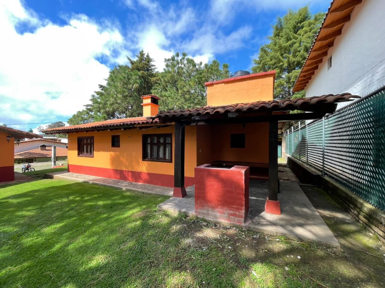 Una casa amb teules, una xemeneia vermella i un pati tancat per una tanca.