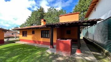 Una casa amb teules, una xemeneia vermella i un pati tancat per una tanca.
