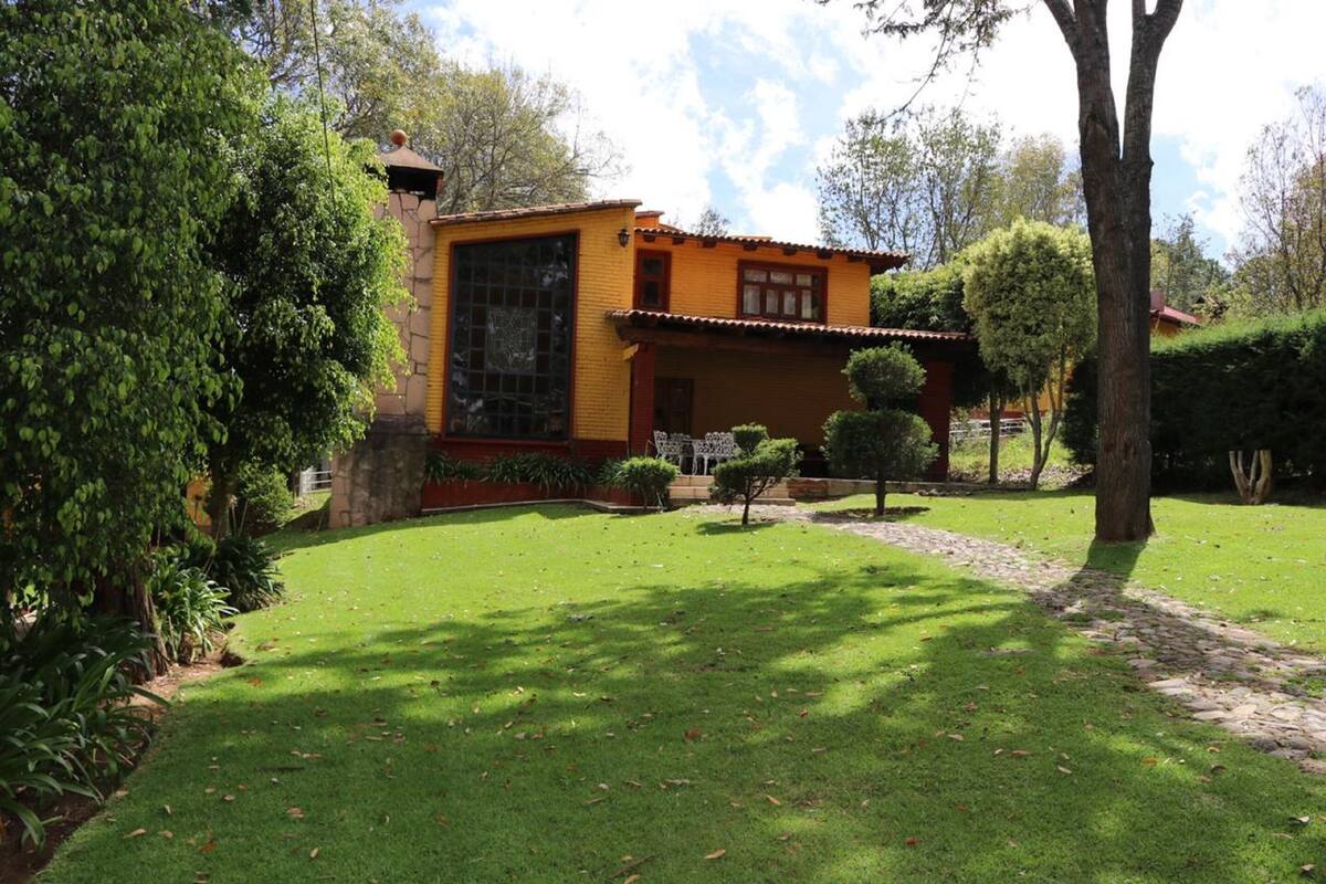 A yellow house with a large window and a small garden with a pathway.