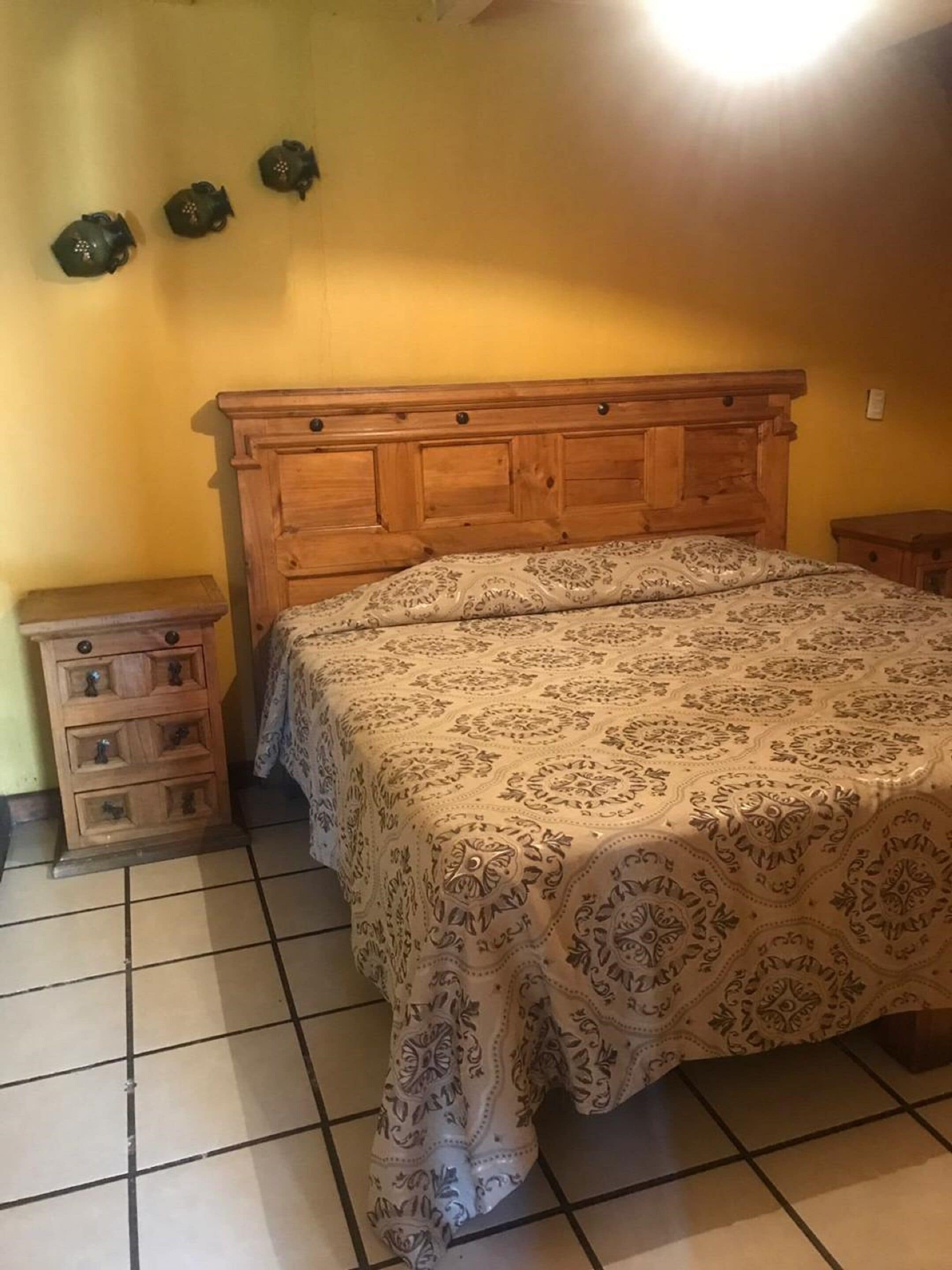 Un dormitorio con una cama de madera, una mesita de noche y un aparador.