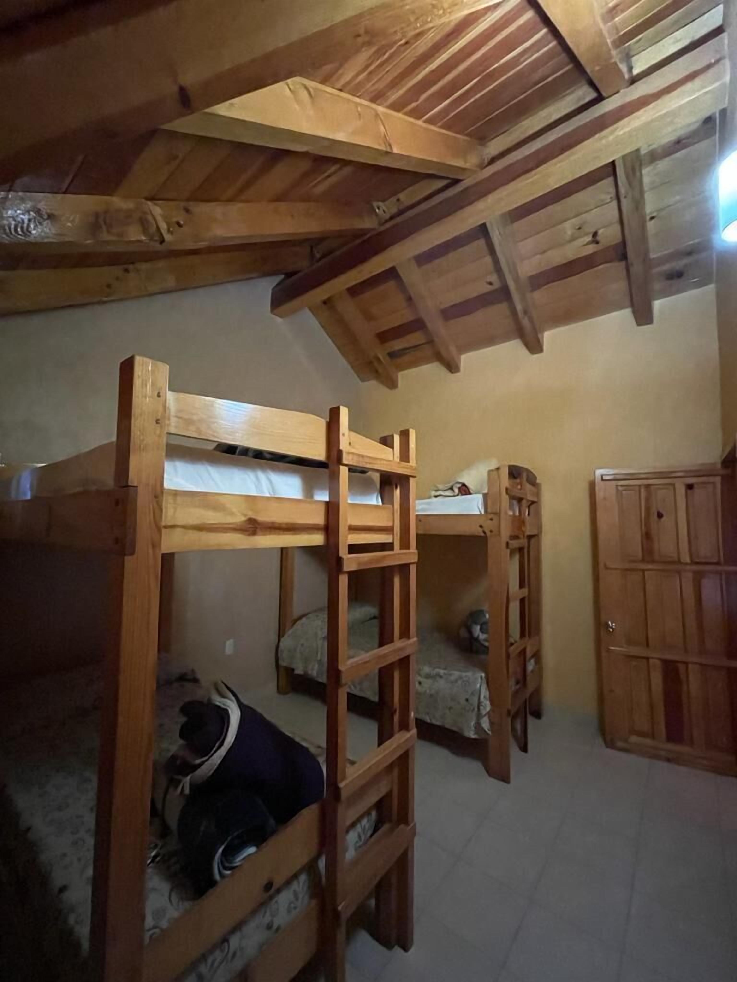 A dormitory room with bunk beds, a ladder, and a wardrobe.