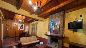 Una sala de estar acogedora con chimenea, muebles de madera y obras de arte en las paredes.