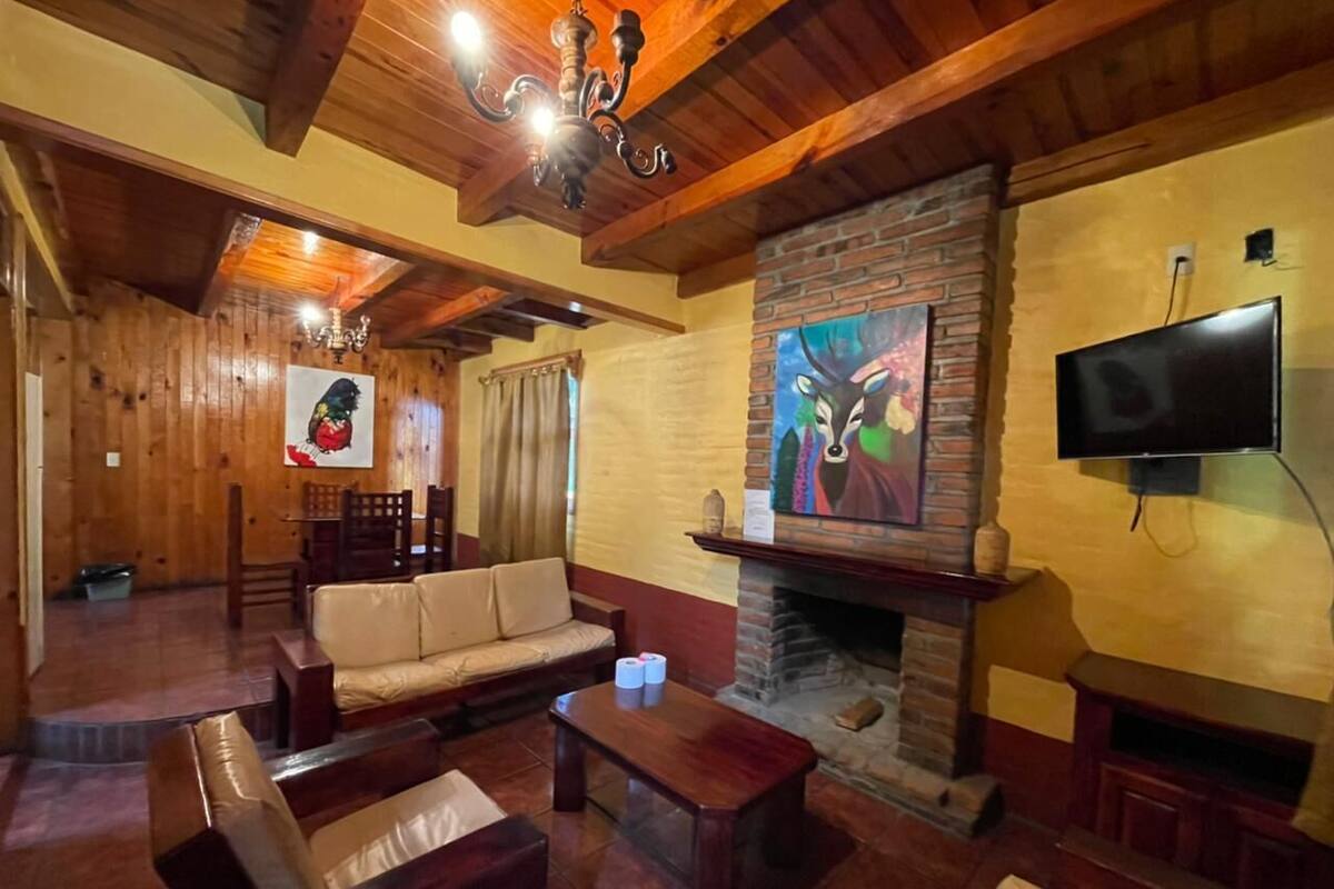 A cozy living room with a fireplace, wooden furniture, and artwork on the walls.