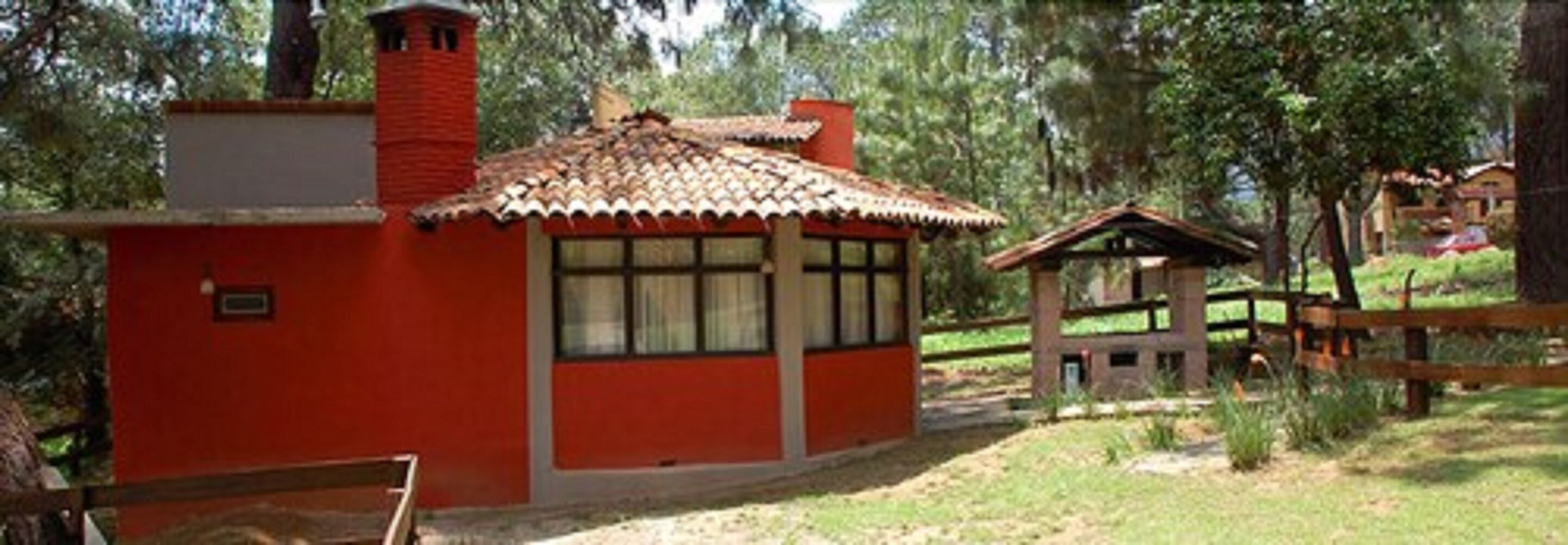 A red building with a tiled roof, a chimney, and a small porch area.
