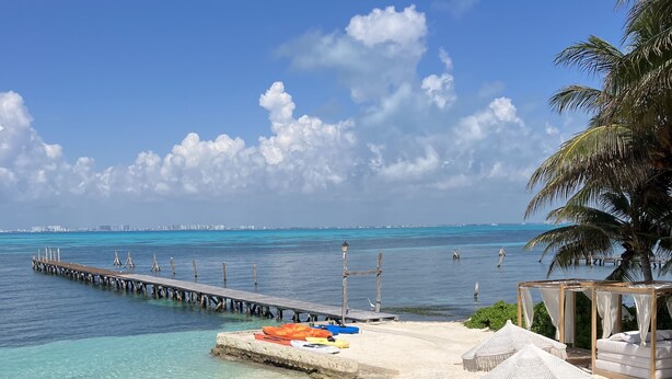 A clear view of a beach with a wooden pier extending into the water, a pool area with steps leading into the water, and a white gazebo with a view of the ocean. - Maria's Kan Kin with Private Beach (Isla Mujeres)