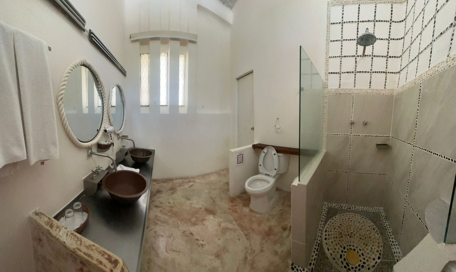 A bathroom with a sink, two bowls, a toilet, and a shower area.