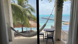 A room with a view of a beach, a hammock, a table, and a chair. - Maria's Kan Kin with Private Beach (Isla Mujeres)
