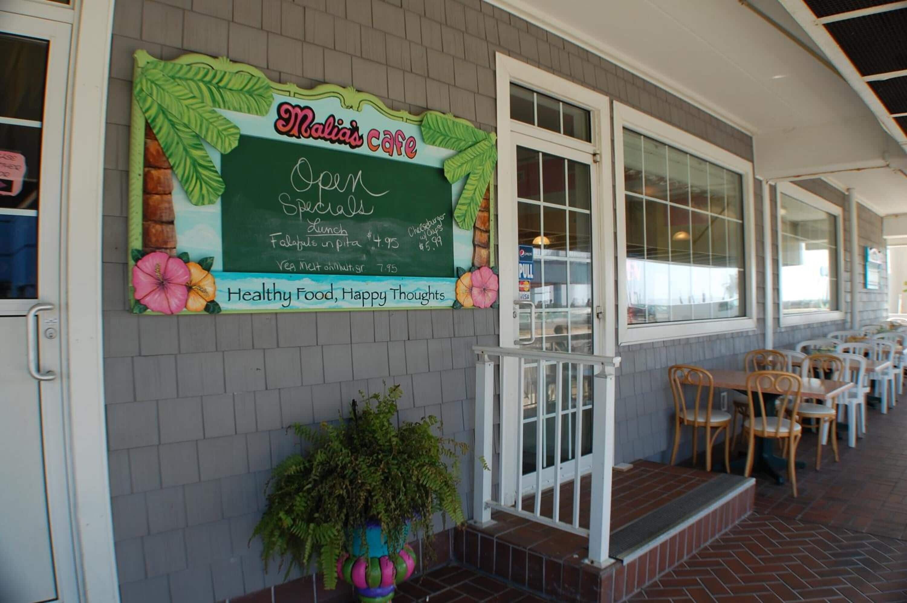 A cafe with a chalkboard sign advertising specials and a patio area with tables and chairs.
