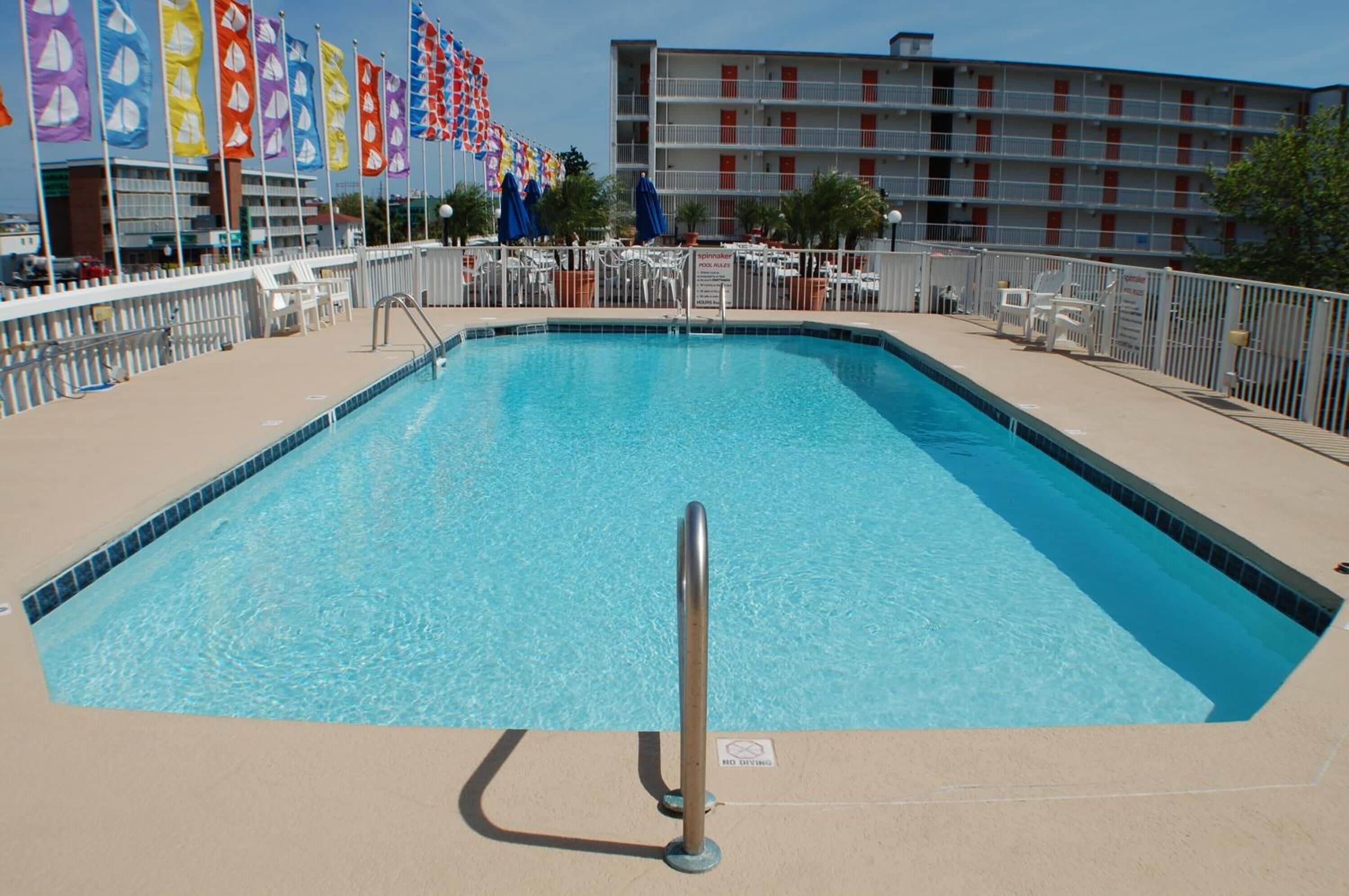 Une piscine rectangulaire avec une rambarde de sécurité en métal au centre, entourée d’une clôture blanche.