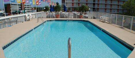 Une piscine rectangulaire avec une rambarde de sécurité en métal au centre, entourée d’une clôture blanche.