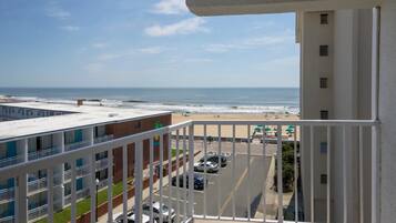 A balcony with a view of the beach and ocean.