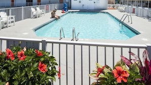 A hotel with a swimming pool, multiple balconies, and a flag display. - The Spinnaker Hotel (Ocean City)