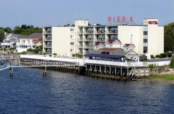 A hotel named Pier 4 with a waterfront view, multiple floors, and a dock extending into the water. - Pier 4 Hotel (Somers Point)