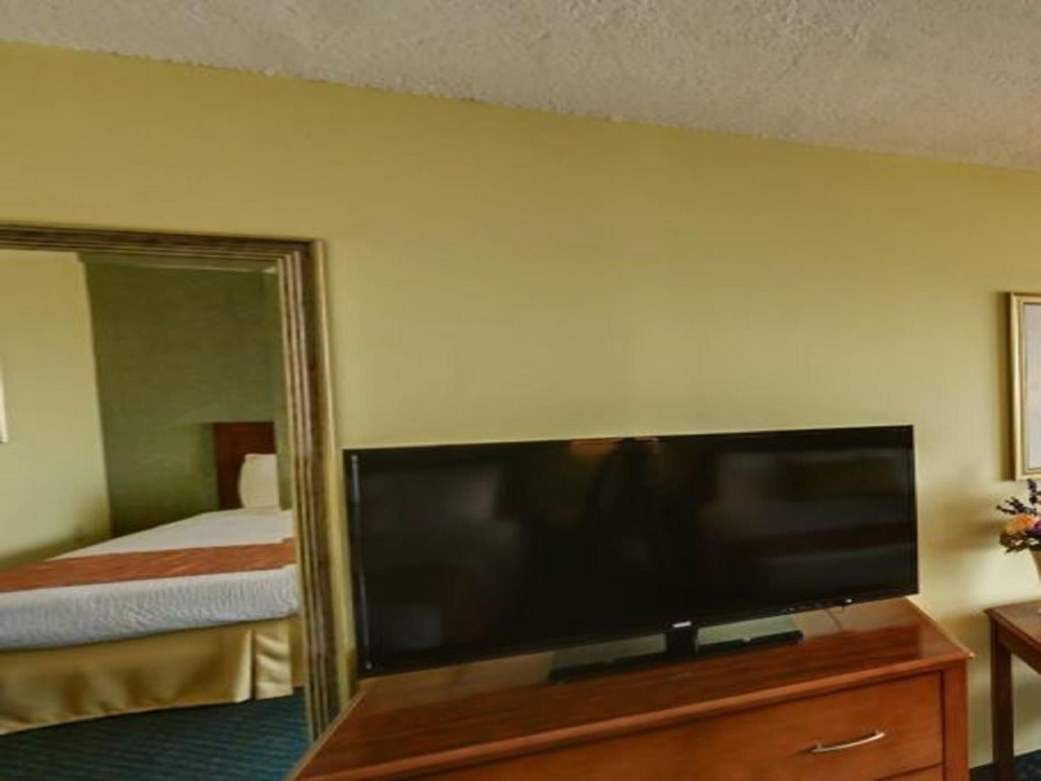 A hotel room with a bed, a TV on a wooden stand, and a small table.