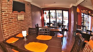 Een restaurant met bakstenen muren, houten tafels en oranje stoelen.