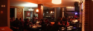 Un restaurante con varias mesas y sillas, una zona de bar y una pared de ladrillo.