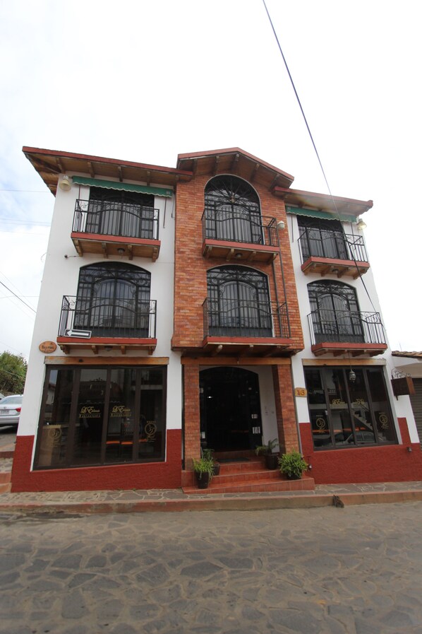 A two-story building with a brick facade, multiple balconies with metal railings, and large windows. - Hotel Real de la Sierra (Mazamitla)