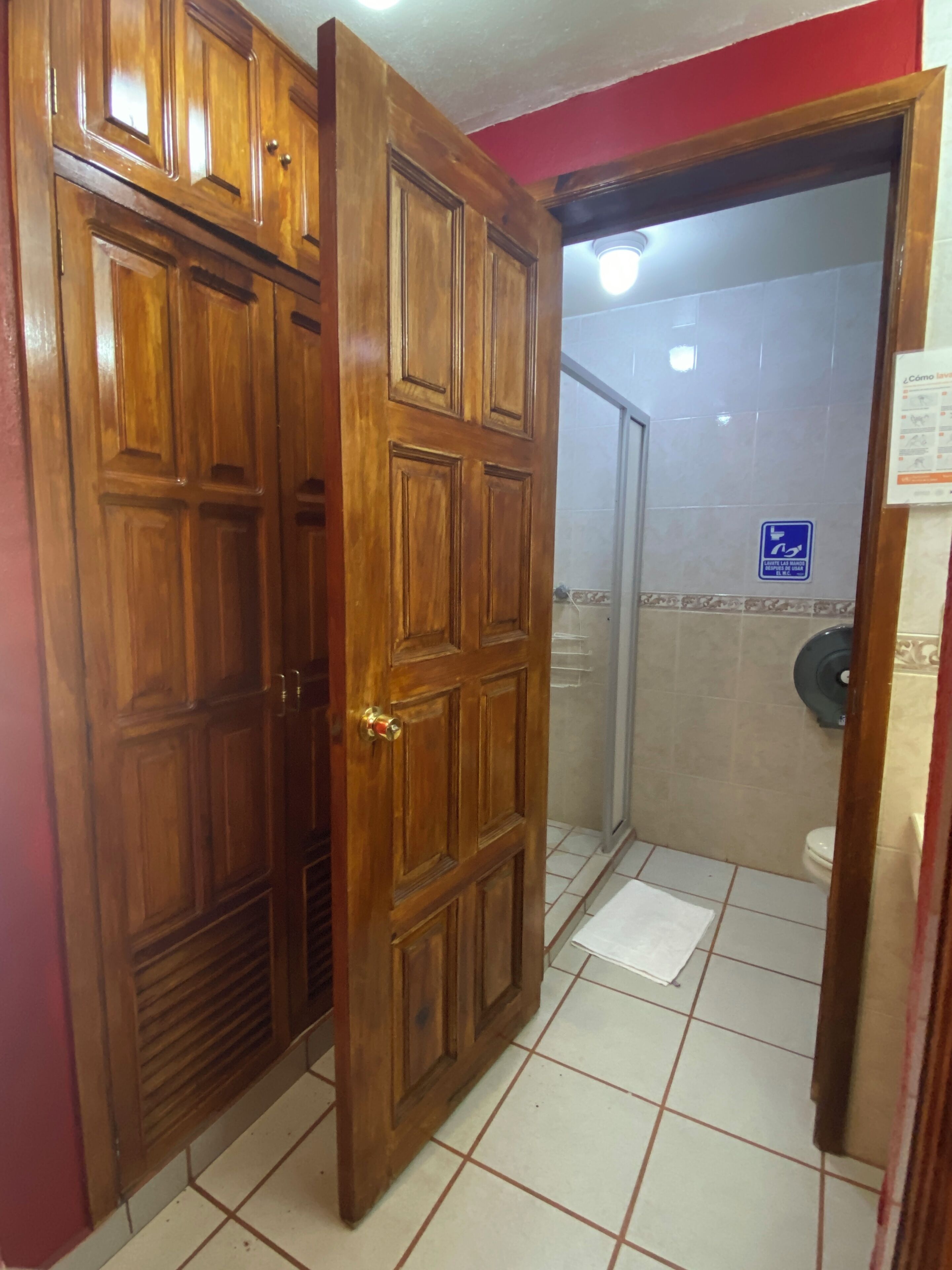Puerta de madera que da a un baño con inodoro y ducha.