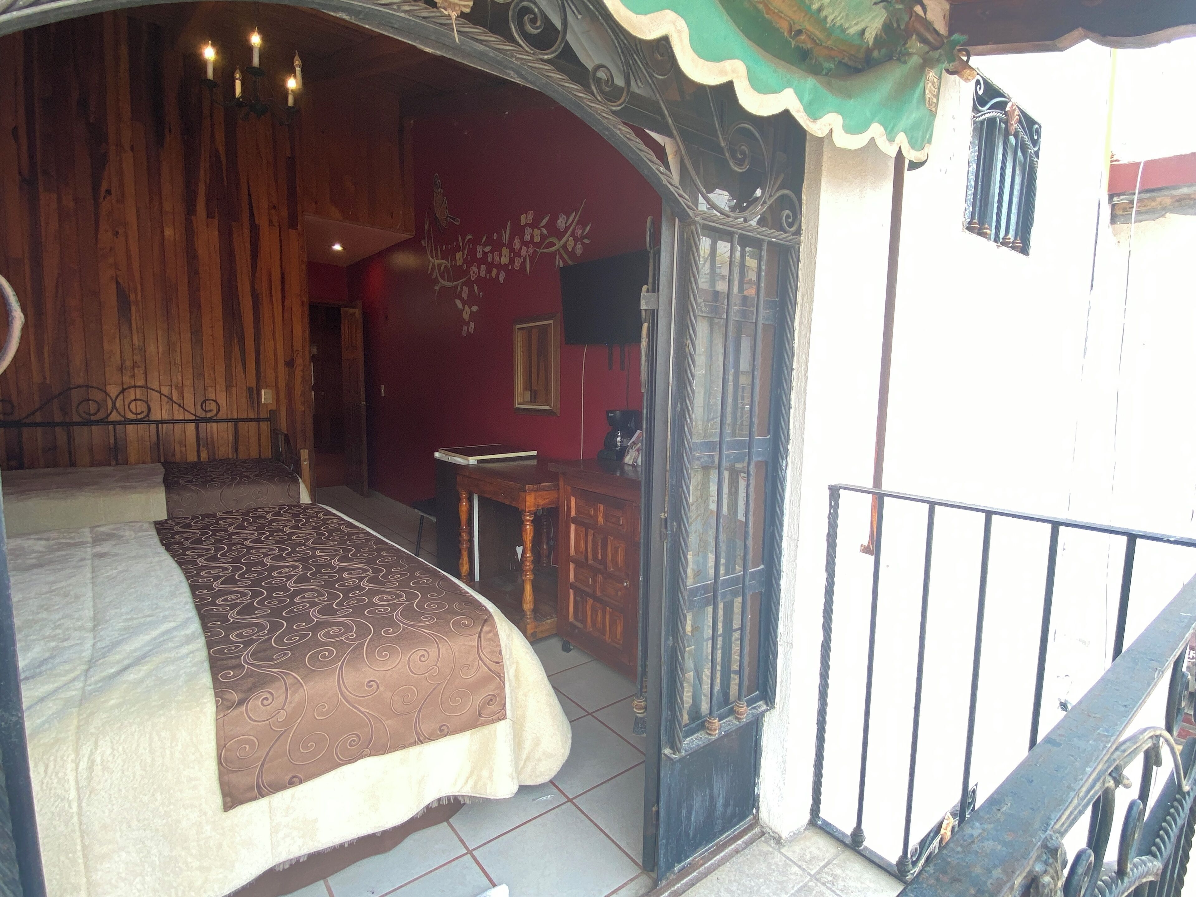 Un dormitorio con cama, una puerta de madera y una mesita.