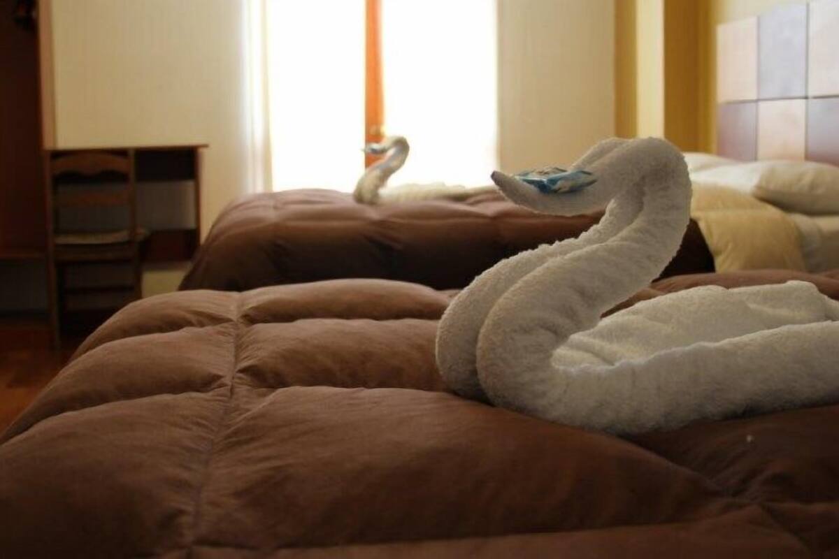 Un lit avec une couette marron et un oreiller en forme de cygne blanc.