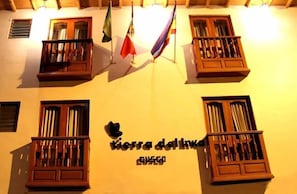 A building facade with multiple windows, some with wooden shutters, and a sign reading "tierra del link" with a butterfly logo. - Tierra del Inka (Cusco)