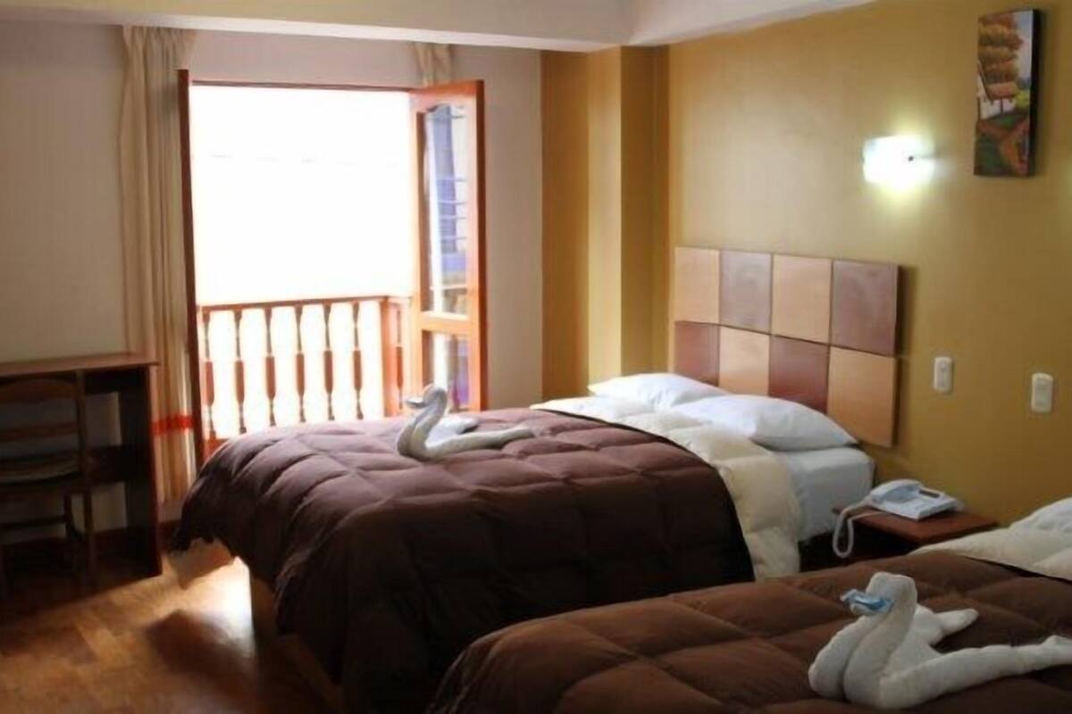 Une chambre d’hôtel avec deux lits, un bureau et un balcon.