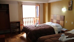 Habitación de hotel con dos camas, un escritorio y un balcón.
