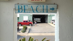 An exit sign for 'Beach' with a directional arrow, a red truck, and a person walking towards a building entrance. - Thunderbird Beach Motel (Ocean City)