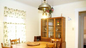 Een eetkamer met een houten tafel en stoelen, een kast met glazen deuren en een hanglamp.