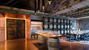 A restaurant with a rustic interior, featuring wooden barrels as tables and a brick wall with wine barrels. - Amilla Maldives (Finolhas Island)
